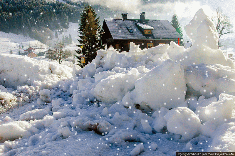 Снегом укрыты дома. Снегопад. Пушистый снег. Зимний домик с падающим снегом. Много снега.